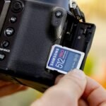 Hand inserting an SD memory card into a camera for storage management
