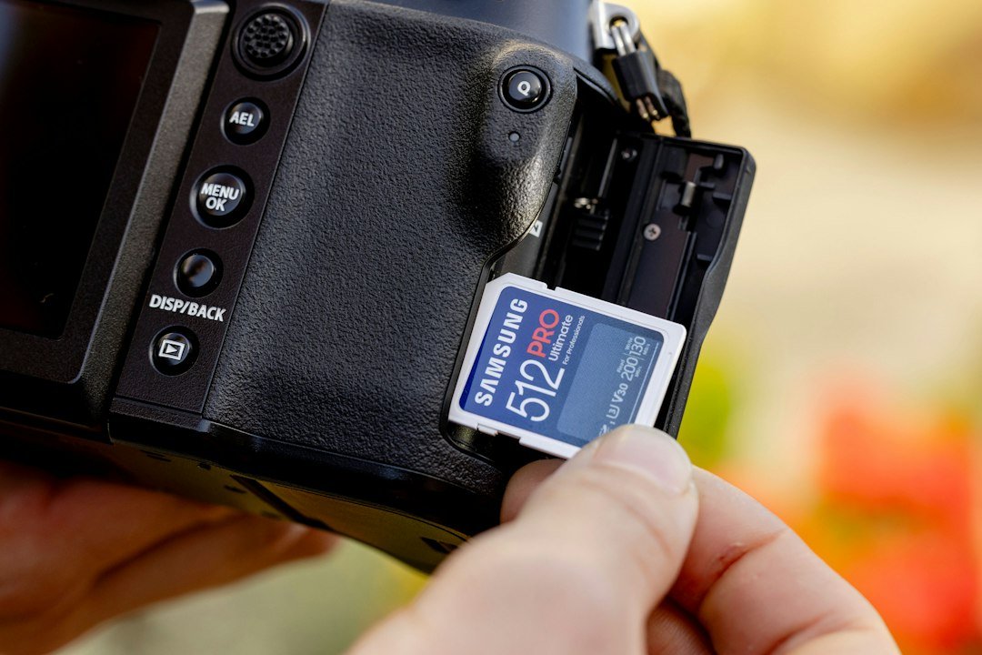 Hand inserting an SD memory card into a camera for storage management